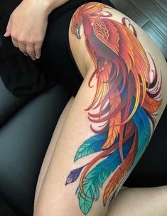 a woman's thigh with a colorful bird tattoo on her leg, sitting in a chair