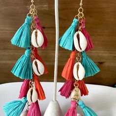 Make a big splash with our multi-color raffia tassel earrings! 🎉 Featuring effortlessly elegant, sleek cowrie shells and vibrant boho-chic tassels, these statement makers are the ultimate beach vibe upgrade. Rock the beachy vibes and turn heads with our multi-color version! 🌈 Let these fabulously chic beachy statement makers tassels sway down to on your shoulders! They're extra-long, pure luxe, lightweight and comfortable.🌴 Features Material: Cowrie Shell and Raffia Drop length: 6.5 inches; w Bohemian Dangle Earrings For Beach, Fringe Earrings For Vacation, Summer Tassel Dangle Earrings With Latkans, Summer Latkans Tassel Dangle Earrings, Summer Tassel Dangle Earrings, Blue Bohemian Tassel Earrings For Summer, Bohemian Blue Tassel Earrings For Summer, Summer Latkan Tassel Dangle Earrings, Chic Summer Fringe Jewelry