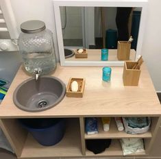 a bathroom with a sink, mirror and shelves on the wall next to toiletries