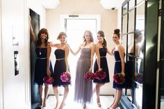 four bridesmaids are standing in front of a mirror and holding their bouquets