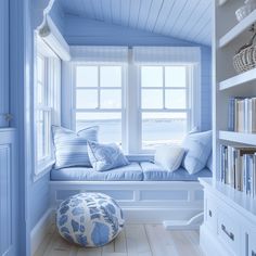 a blue room with a window seat and bookshelf