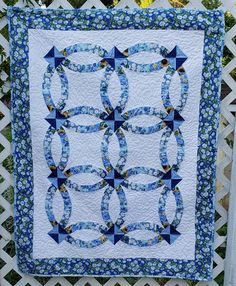 a blue and white quilt hanging on a fence