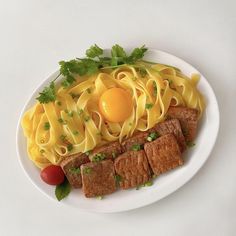 a white plate topped with pasta and meat next to an egg on top of it