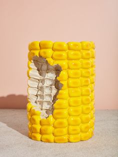 a yellow and white vase sitting on top of a table next to a pink wall