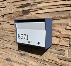 a mailbox mounted to the side of a stone wall