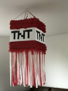 a red and white light hanging from the ceiling with tassels attached to it