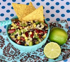 a blue bowl filled with corn, black beans and guacamole next to a lime