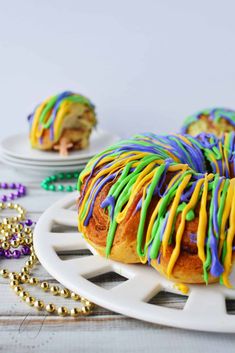 two donuts with colorful icing sitting on a plate next to beads and beaded necklaces