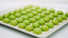 a white plate topped with green candies on top of a table