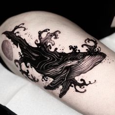 a black and white photo of a woman's thigh with a whale tattoo on it