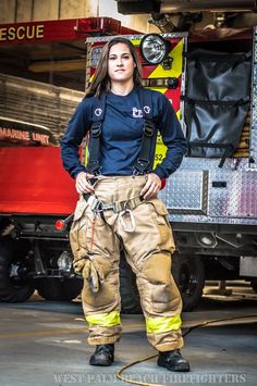 a woman standing in front of a firetruck with her hands on her hips