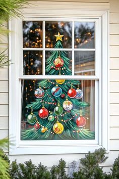 a christmas tree painted on the window sill with ornaments hanging from it's sides