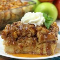 a slice of apple pie on a plate with whipped cream and apples in the background