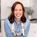 a smiling woman with an apron on in the kitchen