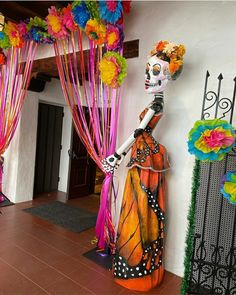 a statue of a woman with flowers on her head in front of a doorway decorated for day of the dead