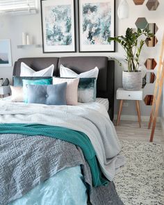 a bed with blue and white pillows in a bedroom next to two pictures on the wall