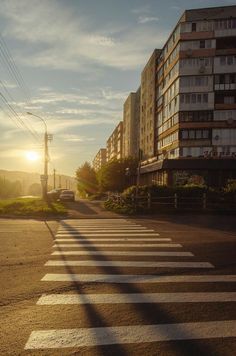 the sun is setting on an empty city street