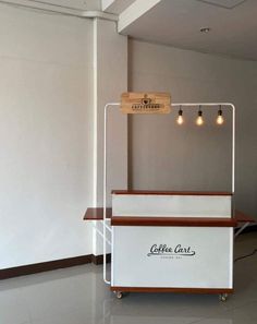 a coffee cart with lights hanging from it's sides in an empty room next to a wall