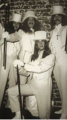 a group of people dressed in white posing for a photo with hats and canes