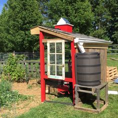 a small red shed with a barrel next to it