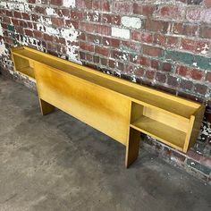 a wooden shelf sitting next to a brick wall