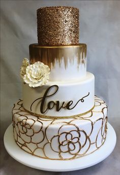 a white and gold wedding cake with flowers on top