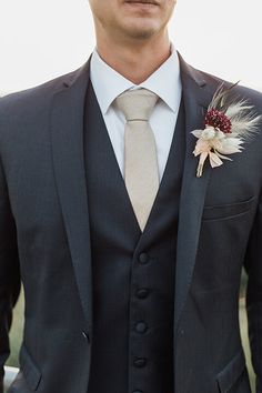 a man wearing a suit and tie with a boutonniere on his lapel