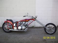 a red motorcycle parked next to a white brick wall