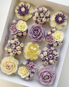 a box filled with purple and yellow cupcakes on top of a white table