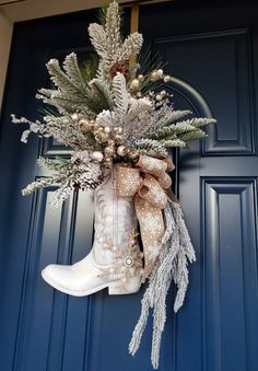 a christmas wreath hanging on the front door with cowboy boots and pine cones in it