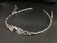 I've fabricated a true Celtic inspired bridal wedding circlet with ornate woven knot extensions holding a center 10mm round Amethyst cabochon gemstone. The circlet is entirely in sterling silver. I've added luxurious detailing around the center stone with four ivy leaves, two on each side, so that the weaves of Celtic knotwork, intertwine with the wires of silver braiding, in and out, throughout the headpiece and leaf work. For a matching pendant necklace, also set with an 8mm gemstone, can be f Handmade Teardrop Crown Headpiece For Weddings, Handmade Teardrop Crown Jewelry For Wedding, Handmade Wedding Jewelry Headband, Handmade Round Crown Wedding Headpieces, Handmade Wedding Headpieces With Round Crown, Handmade Adjustable Headpieces For Wedding, Adjustable Handmade Headpieces For Wedding, Handmade Adjustable Headband For Weddings, Traditional Adjustable Wedding Headband