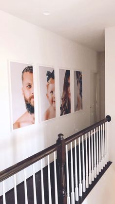 three pictures hang on the wall above a banister in a hallway with white railings