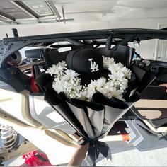 a baseball cap is tied to the back of a car with flowers in front of it