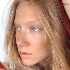 a close up of a woman with blue eyes and piercing on her nose looking at the camera