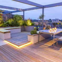 an outdoor dining area is lit up with candles and greenery on the roof terrace