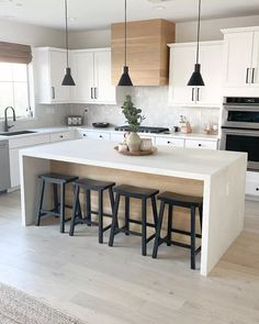 a kitchen island with stools in front of it and two lights hanging from the ceiling