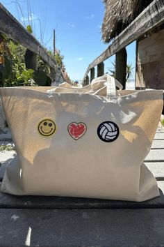 a white tote bag sitting on top of a wooden bench next to a building