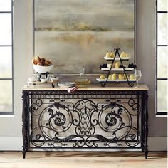 a buffet table with food on it in front of a large painting and two windows