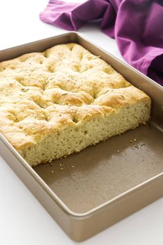 a loaf of bread sitting on top of a pan next to a purple napkin and fork