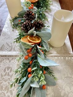 the table is set with candles, orange slices and greenery