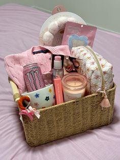 a wicker basket filled with baby items on a pink bed spreaded in white