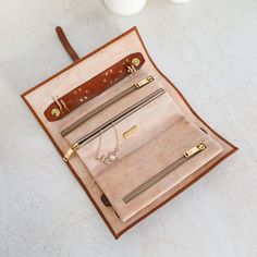 an open leather purse sitting on top of a table next to two white vases