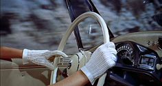 black and white photograph of a woman driving a car with her hand on the steering wheel