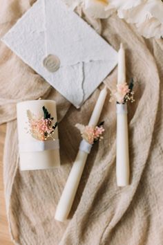 three candles with flowers on them sitting next to an envelope and some paper napkins