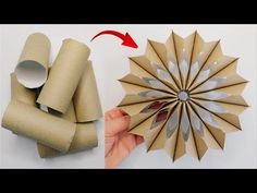 a hand holding a brown paper fan next to some rolls of toilet paper and another piece of cardboard