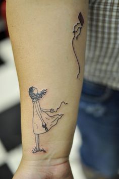 a woman with a kite tattoo on her left arm is holding the string to a balloon