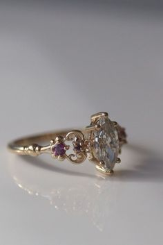 a close up of a ring on a white surface with an oval shaped diamond in the center