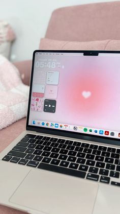 an open laptop computer sitting on top of a pink couch next to a white blanket