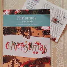 a cross stitch book with christmas designs on the front and back cover, sitting on a table