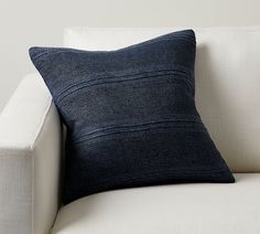 a blue pillow sitting on top of a white couch